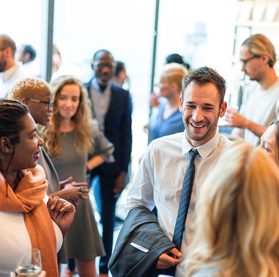 man in a suit smiling at a gathering of people