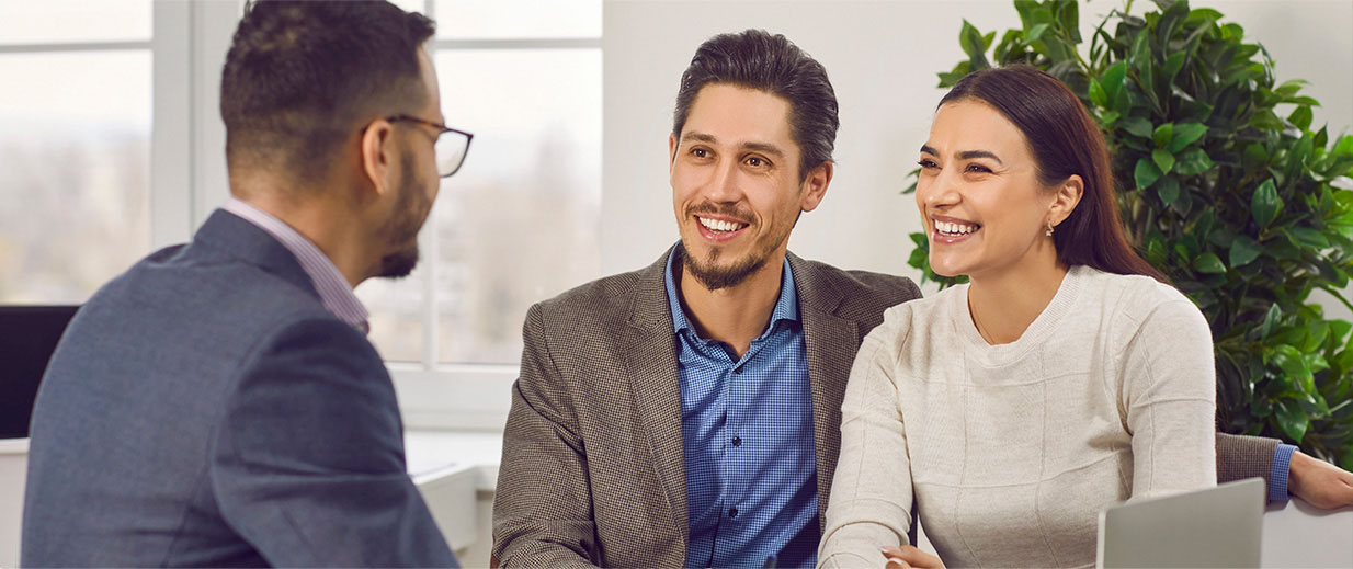 young couple sitting at a meeting with a businessman smiling