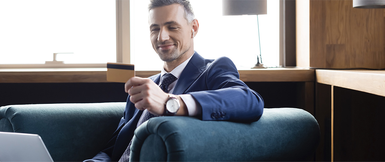business man sitting on a couch smiling looking at a card
