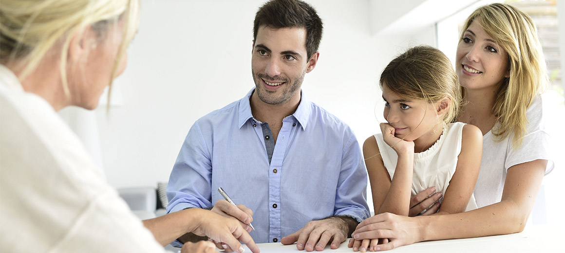 family sitting with a woman signing a paper